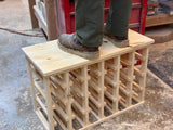 Handcrafted reclaimed wood wine rack showing solid construction with man standing on top shelf of wine rack